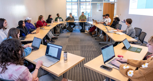 Students sitting at desks arranged in a circle in a classroom