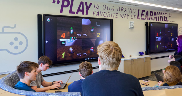 Students socializing gathered around a TV playing Mario Kart