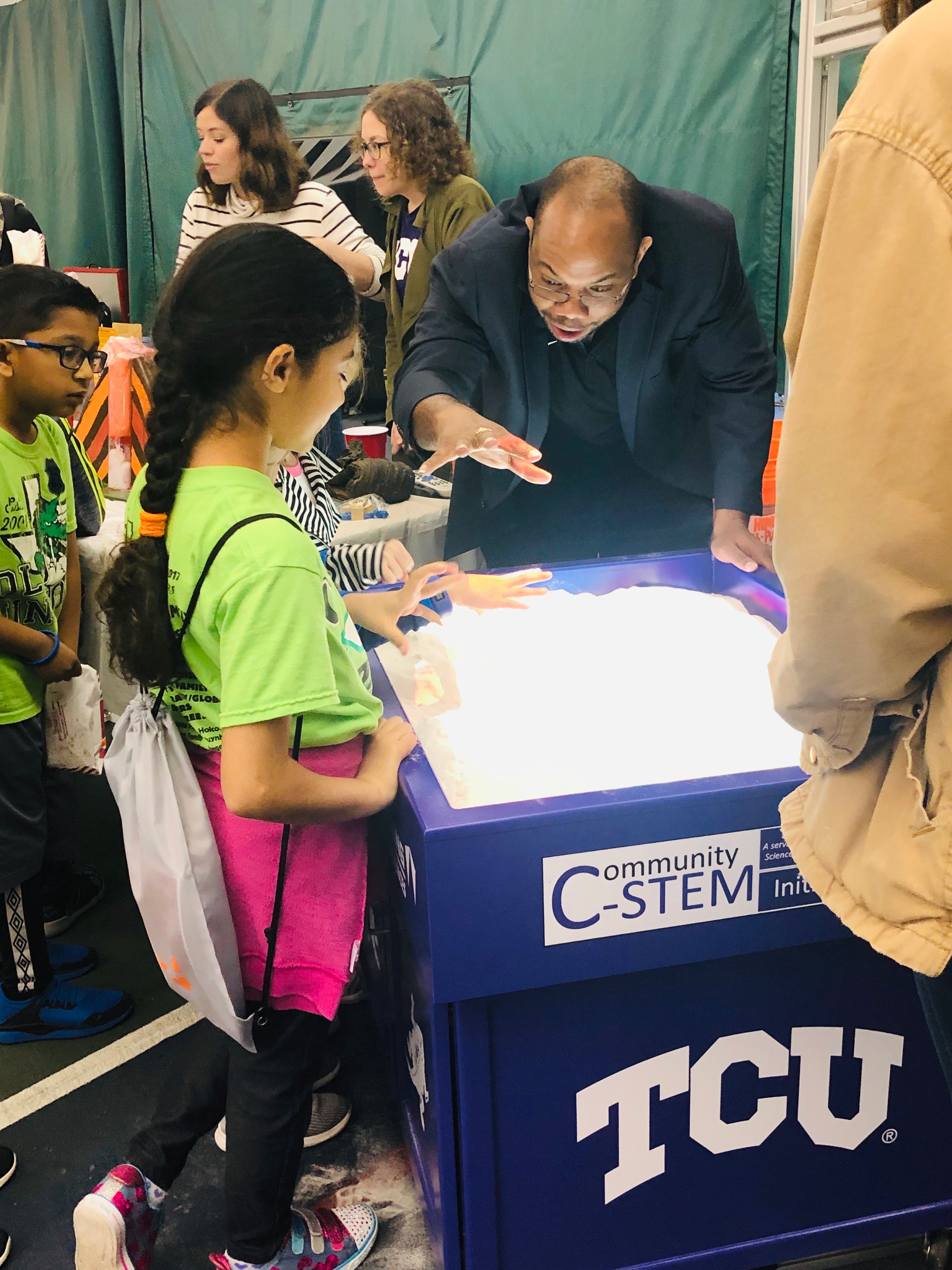 Dr. Harvey explains something using a light table exhibit