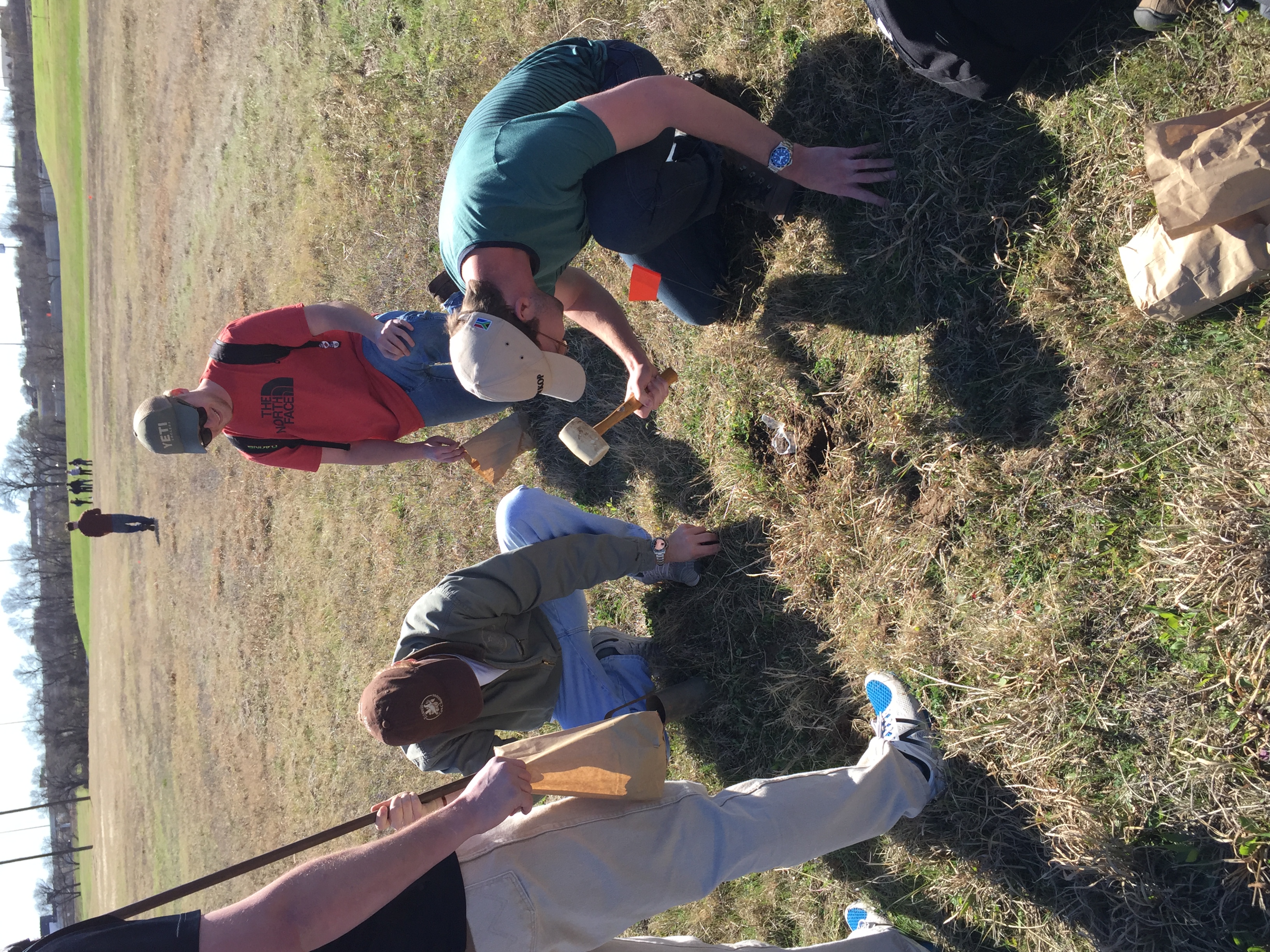 A group of people gather around a soil test site
