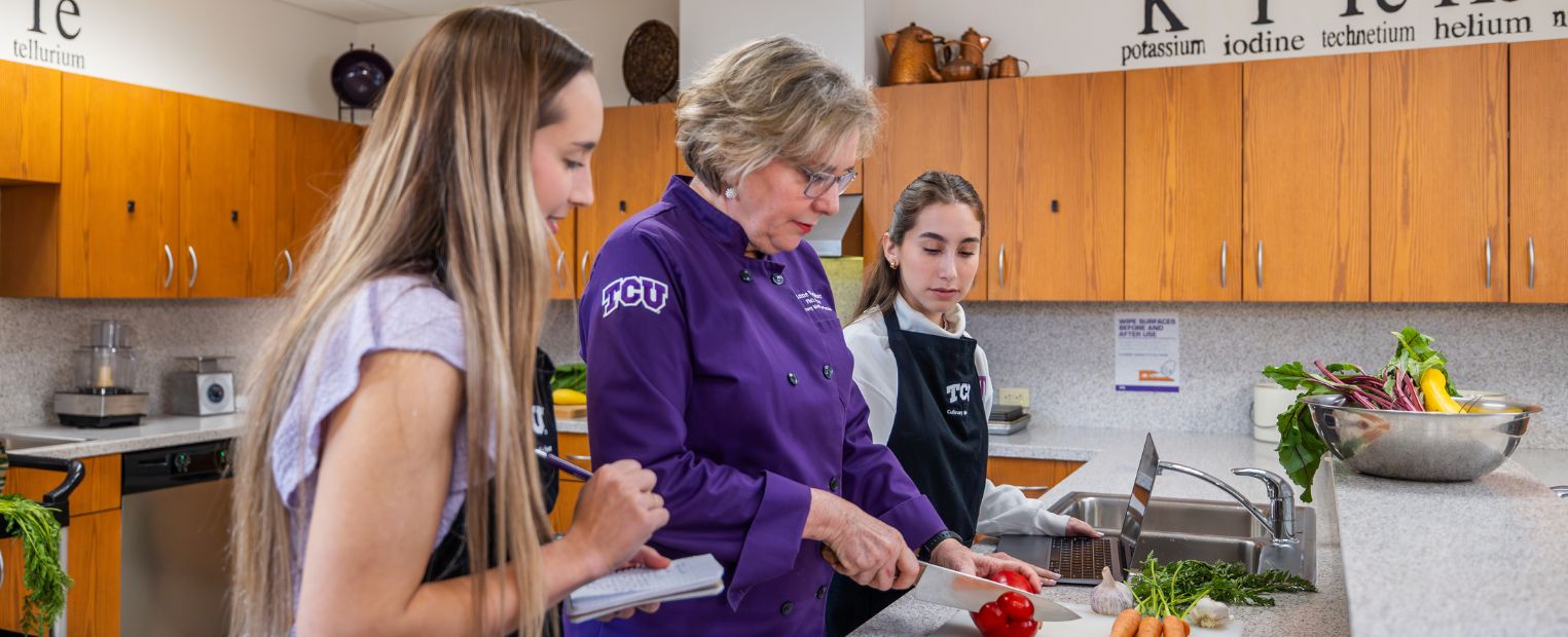Anne VanBeber teaches two students how to chop a pepper.